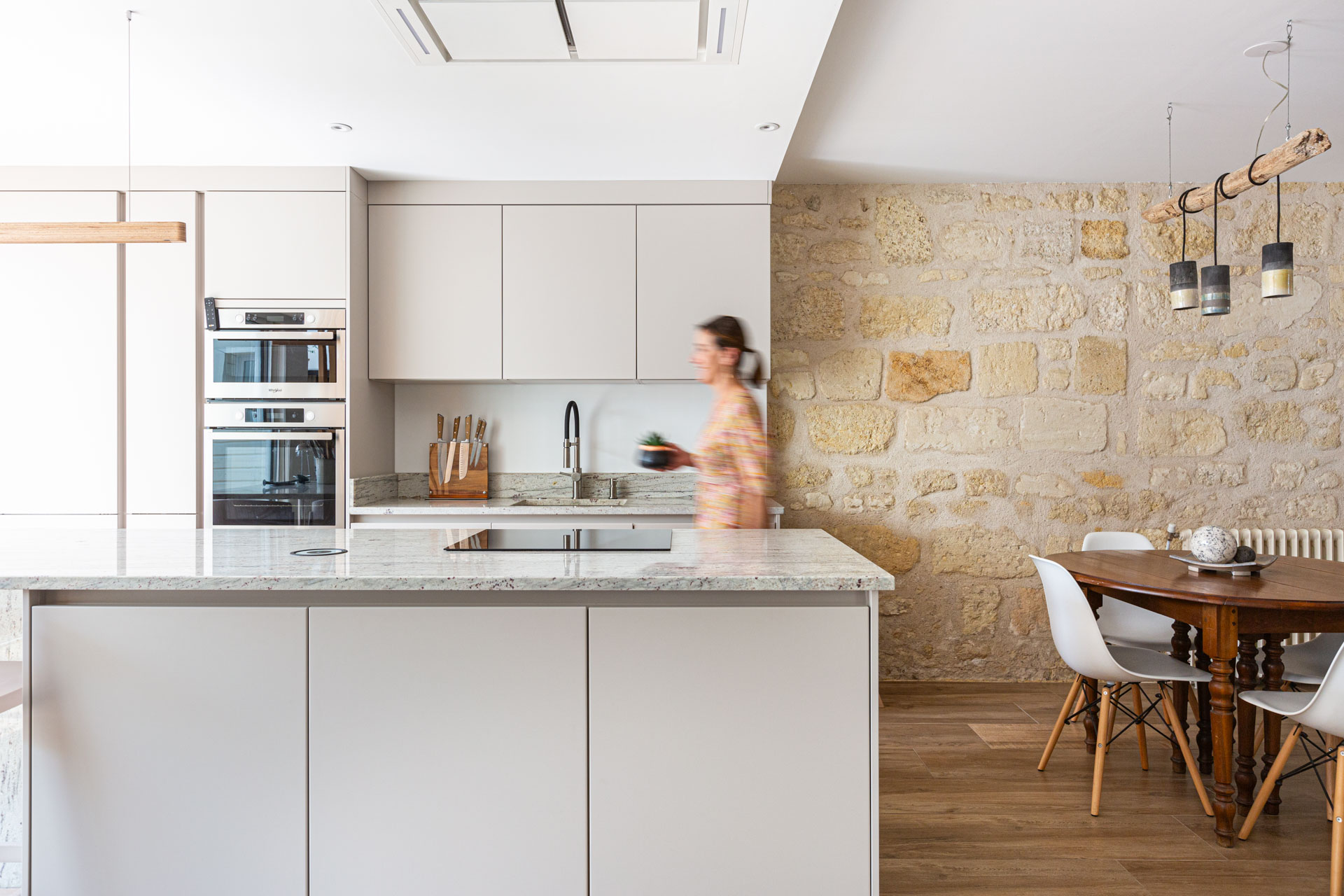 Cuisine contemporaine ouverte, îlot central, mur de pierre derrière la table
