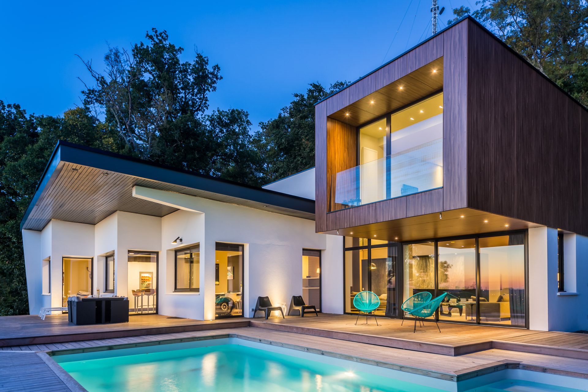 Maison d’architecte photographiée à l’heure bleue, terrasse et piscine éclairées