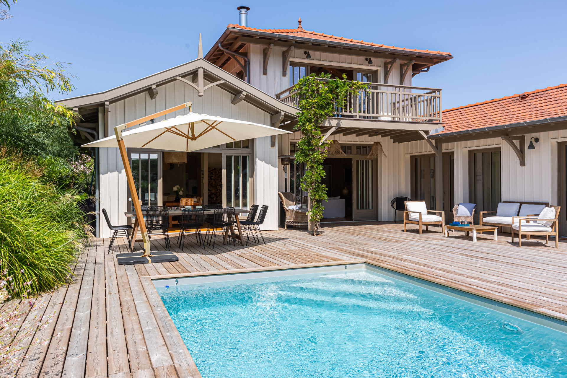 Villa à bardage bois et toit de tuiles, terrasse, piscine et parasol