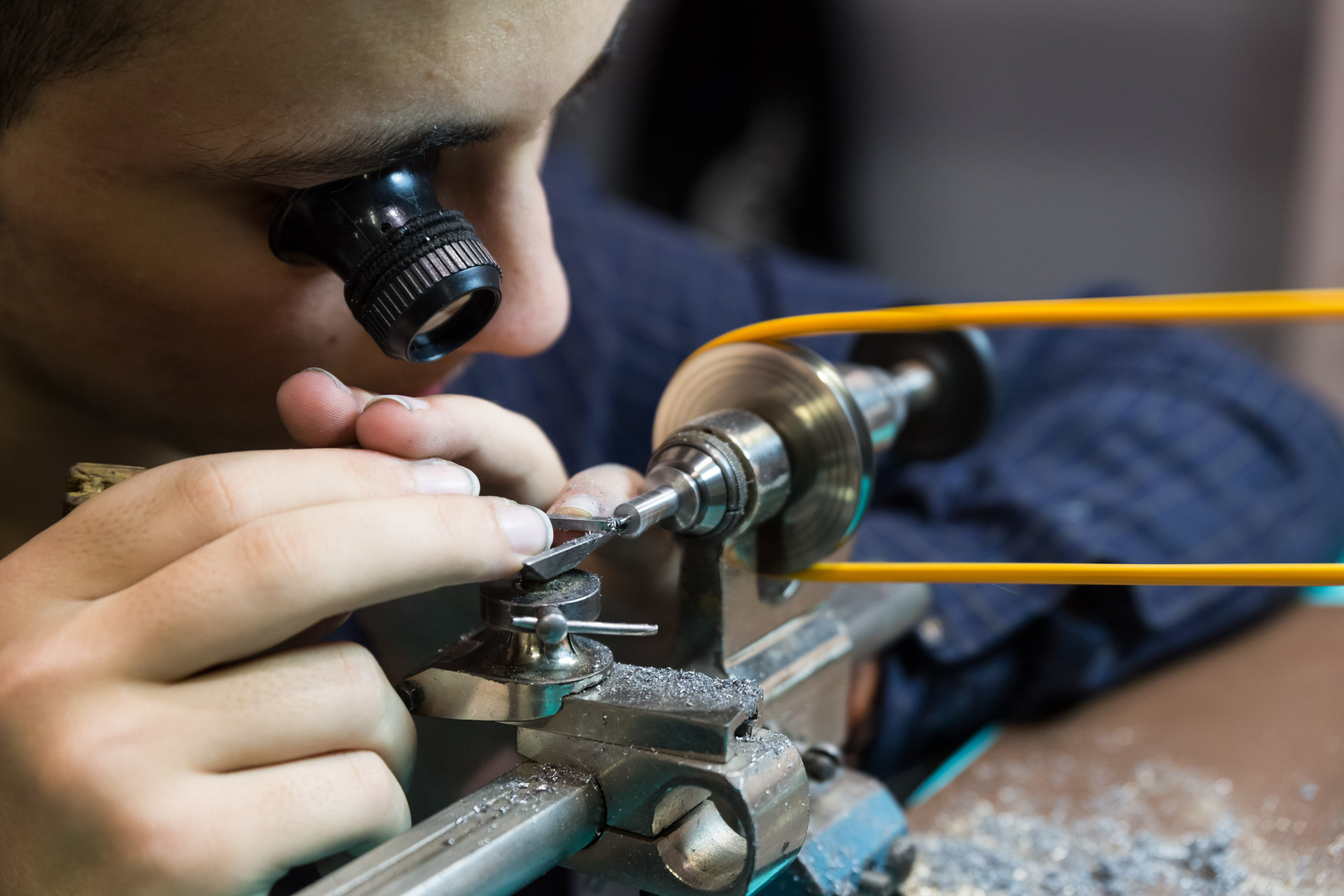 Artisan à la loupe d’horloger, travaillant une pièce sur un tour de précision